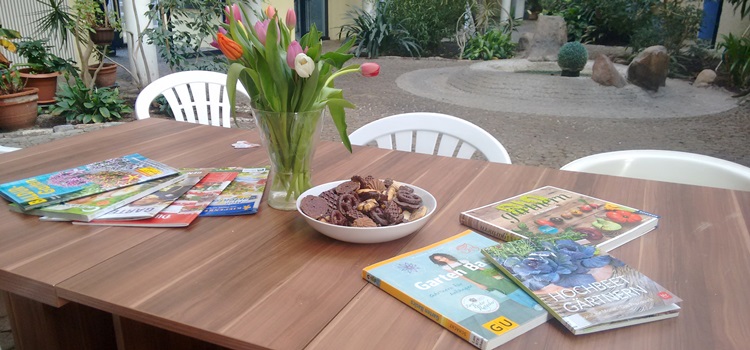 Tisch in einem Atrium, bestückt mit Tulpen, Keksen und Gartenbüchern