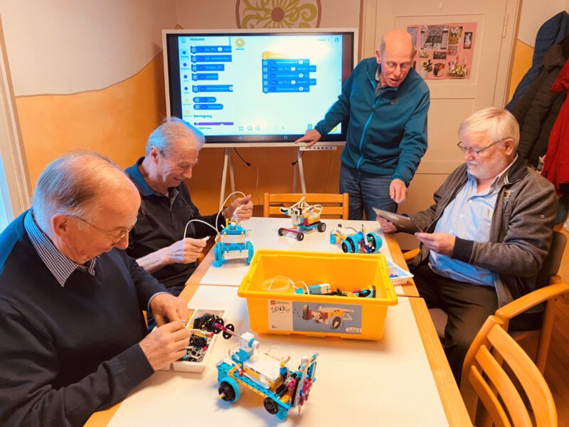 Ältere Männer bauen Legoroboter.